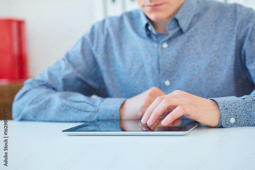 Fototapeta premium Man presses on the blank screen tablet computer. Concept: man working from home using tablet computer. Free space for text.