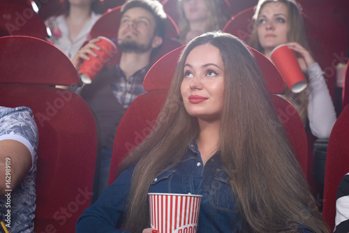 Gorgeous young woman smiling enjoying watching a movie at the local cinema spectator premiere film happiness leisure activity recreation people lifestyle concept.