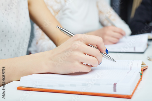 Woman's hand making notes at a business meeting closeup. Business job offer, financial success, certified public accountant concept.