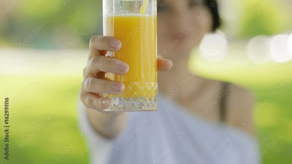 Fresh orange glass of juice in a woman's hands, she give healthy drink Fresh orange glass of juice in a woman's hands, she give healthy drink