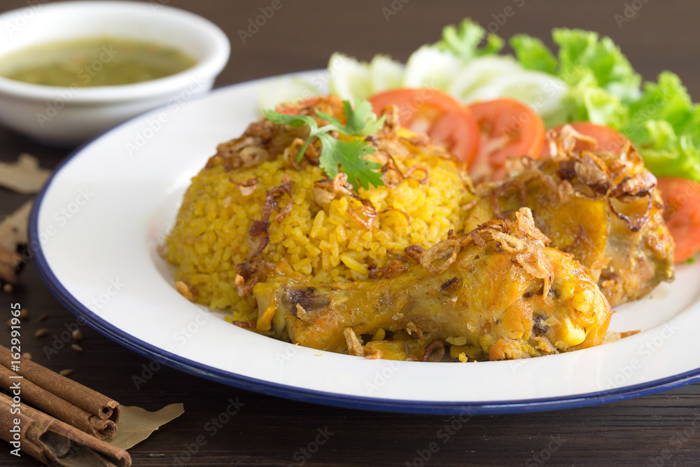Chicken Biryani on white dish with green sauce (Muslim yellow rice with chicken) on brown wooden background.. Chicken Biryani on white dish with green sauce (Muslim yellow rice with chicken) on brown wooden background..