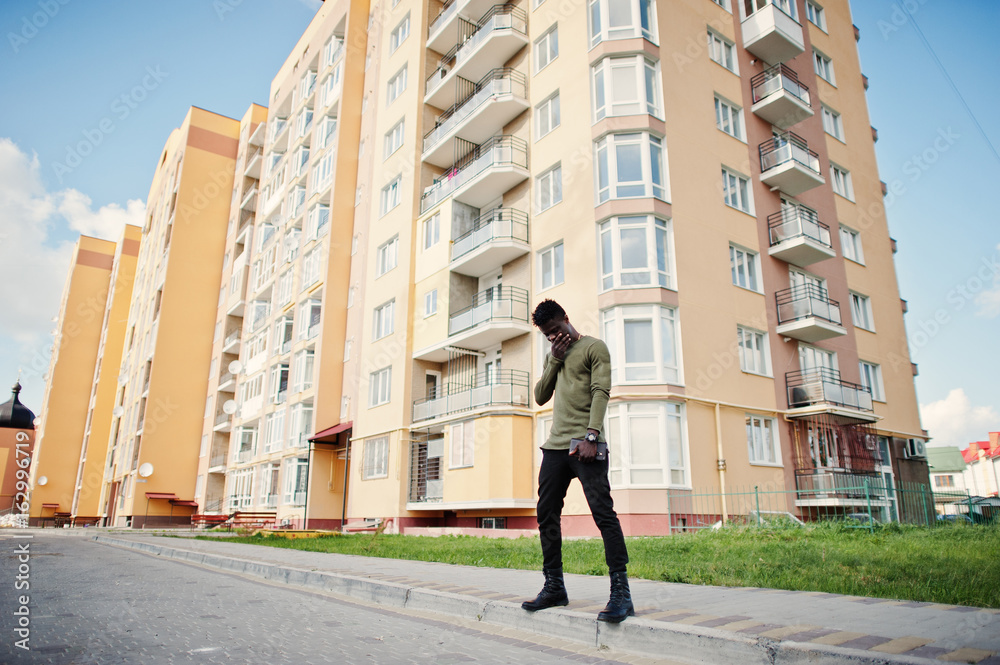Handsome and attractive african american man posing next to the tall building on a street. Handsome and attractive african american man posing next to the tall building on a street.