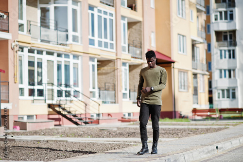 Handsome and attractive african american man posing next to the tall building on a street. © AS Photo Family