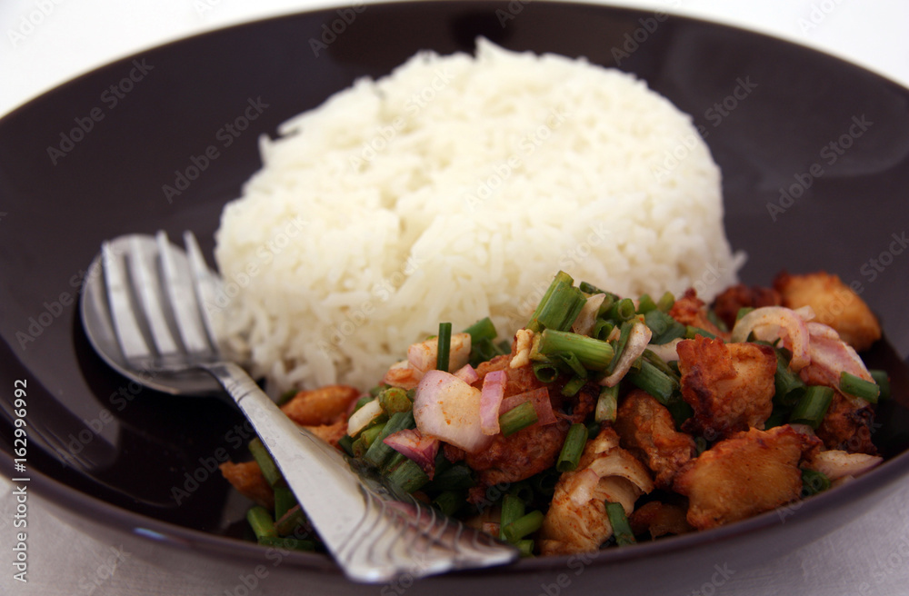 Fried chicken Spicy Salad with Rice in the black dish and cutlery, Food decoration with spring onion. Fried chicken Spicy Salad with Rice in the black dish and cutlery, Food decoration with spring onion.