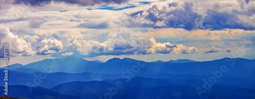 Panorama of mountain ridges with clouds and fog in the morning evening time, at sunrise, sunset