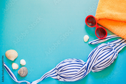 the summer swimming things on a bright background with seashells and sunglasses