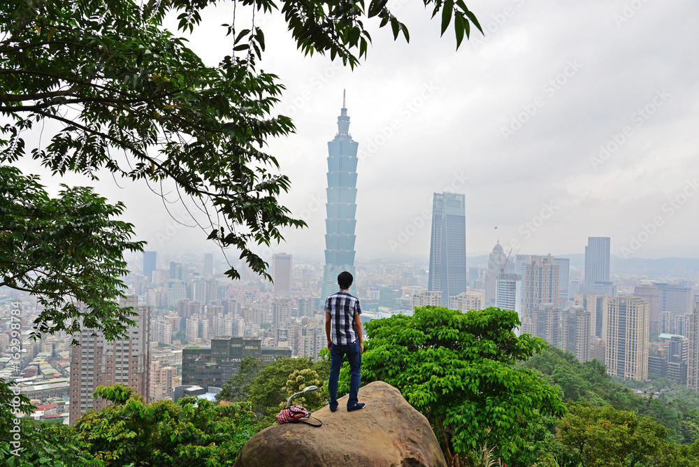 Fototapeta premium 101 tower and city of Taipei with a young man figure viewed from behind.