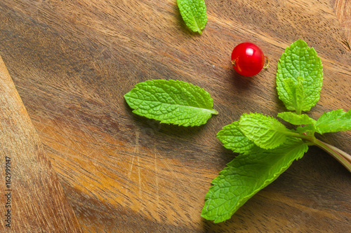Fresh mint leaves and red currants on an old wooden background. Blurred gray background.
