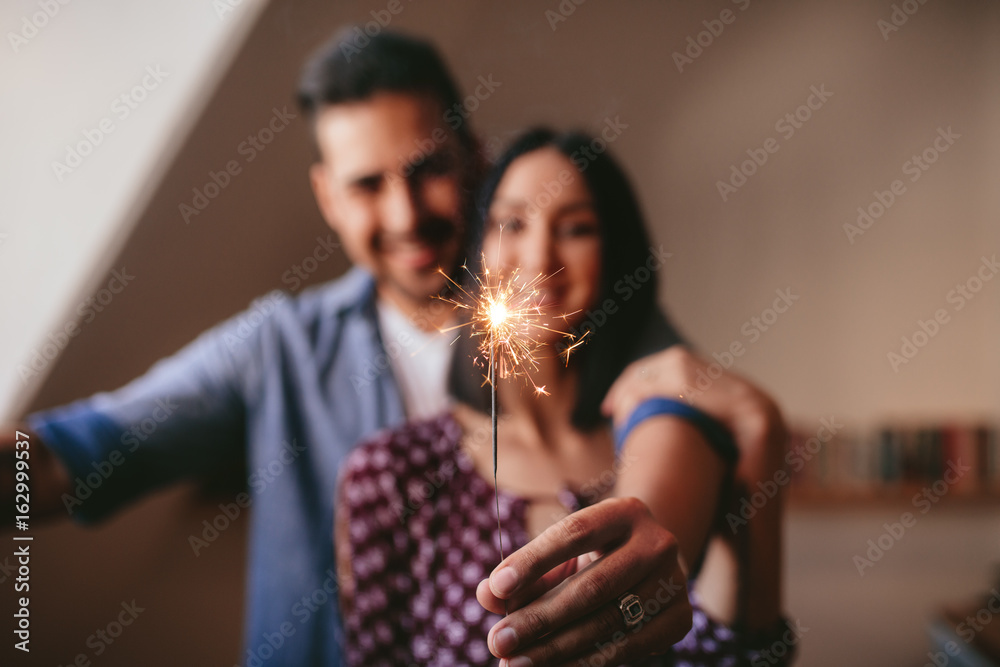 Young couple celebrating with sparkler at home Young couple celebrating with sparkler at home