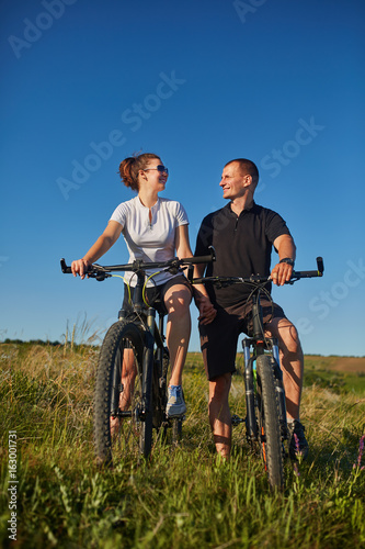 Couple of cyclists riding bicycles in meadow