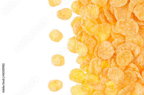 Decorative border of golden cornflakes isolated on white background. Cereals texture.
