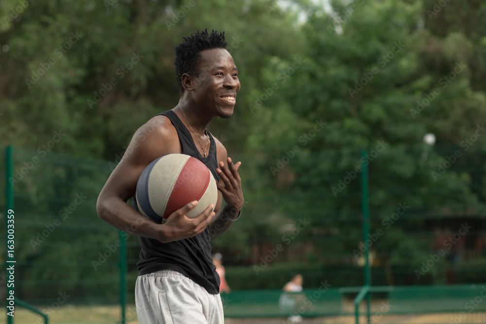 African american man plays on street basketball court. Real and authentic activity.