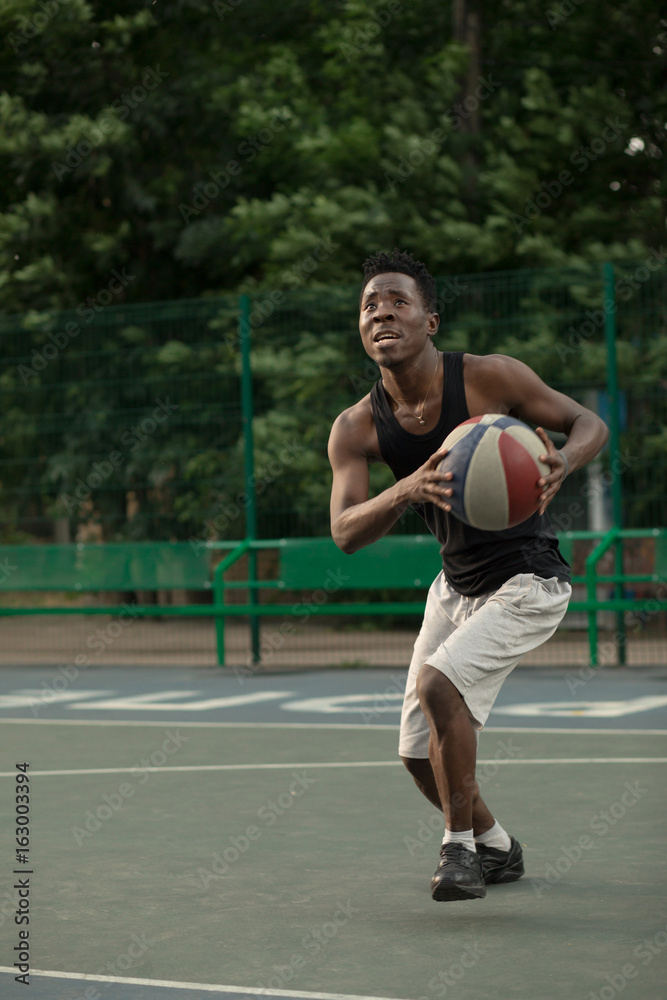 African american man plays on street basketball court. Real and authentic activity.