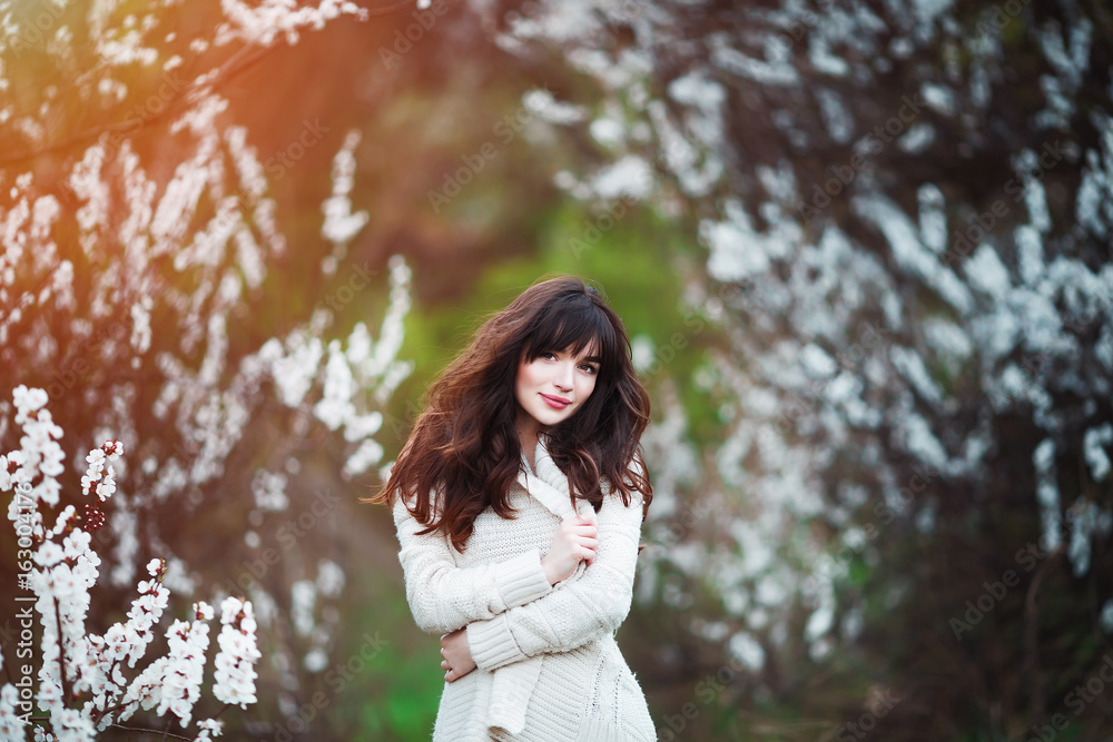 Happy beautiful young woman with long black healthy hair enjoy fresh flowers and sun light in blossom park at sunset. Happy beautiful young woman with long black healthy hair enjoy fresh flowers and sun light in blossom park at sunset.