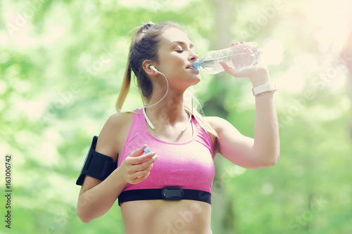 Woman jogging in the forest with bottle of water