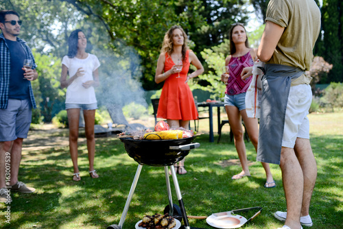 groupe of happy and cheerful young people having fun around barbecue grill during a summer holiday party outdoor in the garden