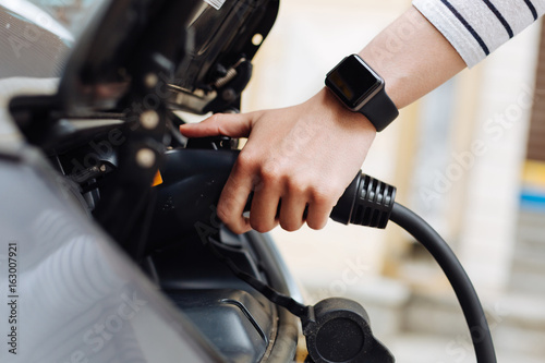 Female hands holding charger for electric car