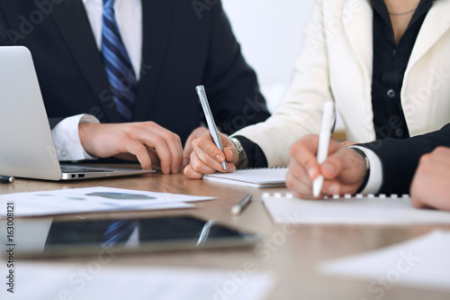 Group of businesspeople or lawyers discussing contract papers and financial figures while sitting at the table. Close-up of human hands at meeting or negotiations. Success and communication concept