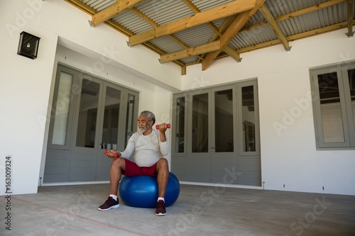 Man exercising with dumbbells on exercise ball 