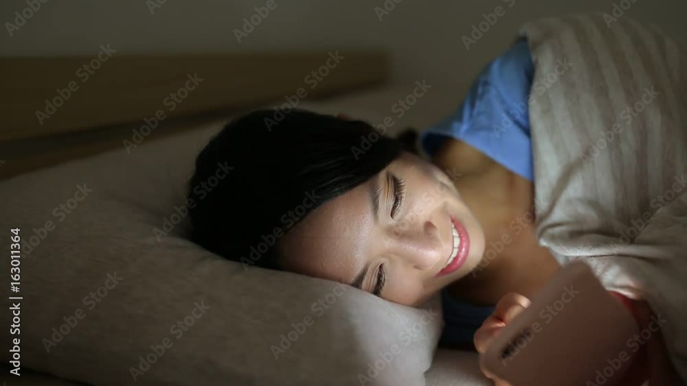 Woman using cellphone in bed at night Woman using cellphone in bed at night