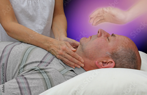 Spiritual help during a healing session - female hands laid either side of a male patient's throat channeling energy together with the help of a higher power on a dark purple background