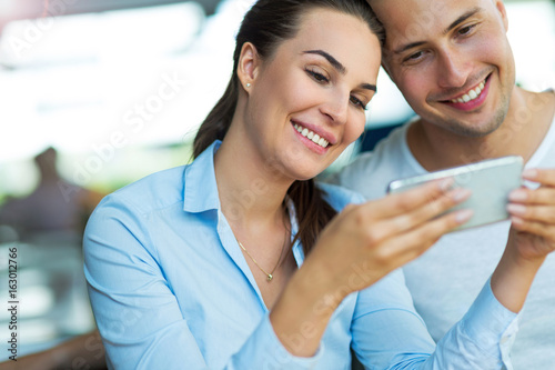 Young couple using mobile phone at cafe  