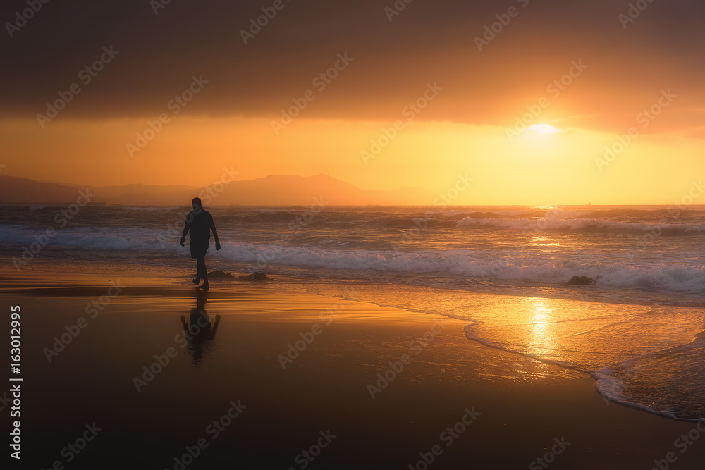lonely person walking on beach at sunset