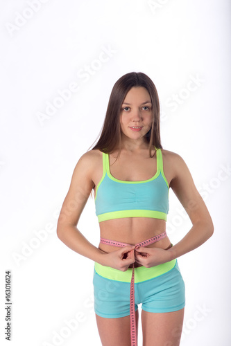 Fitness woman with measuring tape measures waist