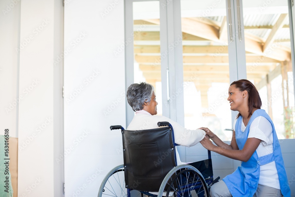 Female doctor interacting with senior woman on wheelchair Female doctor interacting with senior woman on wheelchair