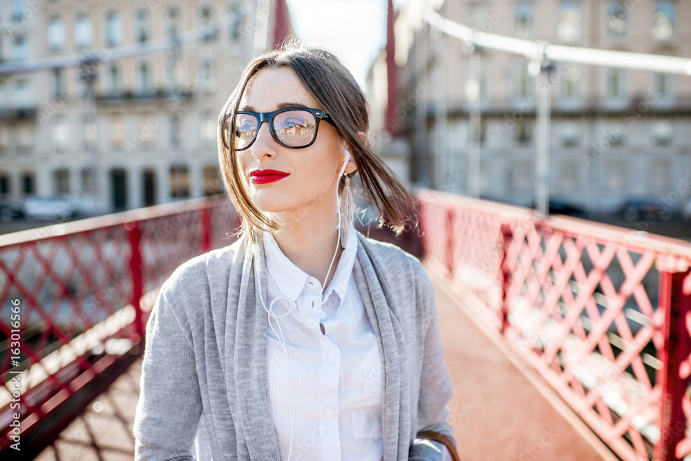 Φωτογραφία Lifestyle portrait of a stylish businesswoman walking on the red bridge in Lyon
