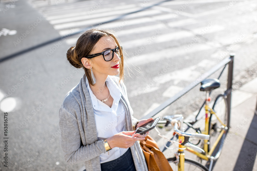 Φωτογραφία Portrait of a young businesswoman standing with phone near the bicycle outdoors