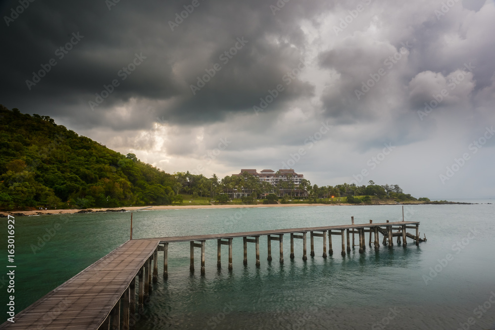 Wooden bridge on sea with rain clouds