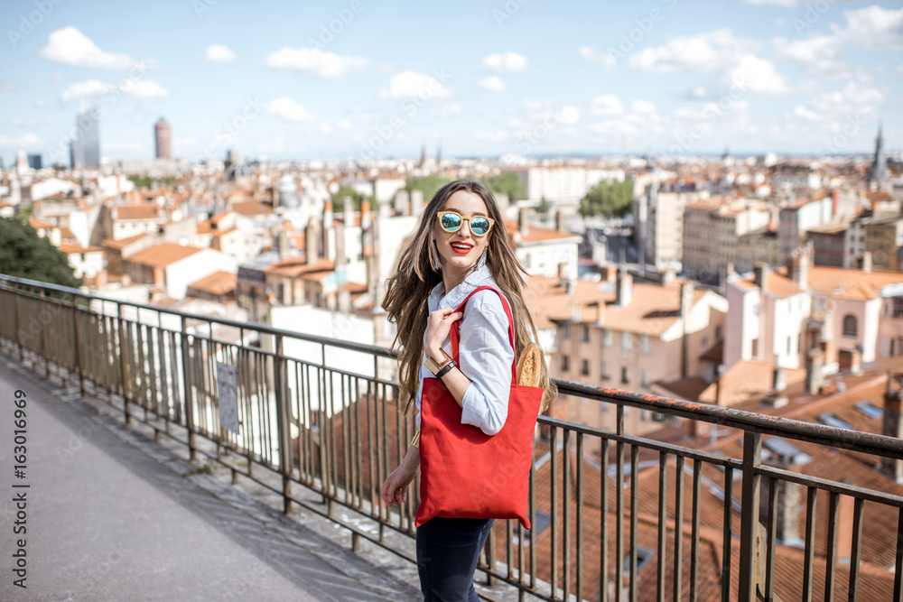 Young woman walking with red bag with great view on Lyon city in France