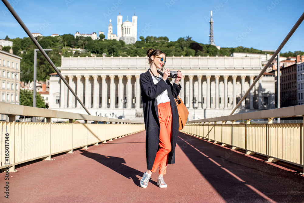 Φωτογραφία Young stylish woman standing with photo camera on the footbridge in the old town