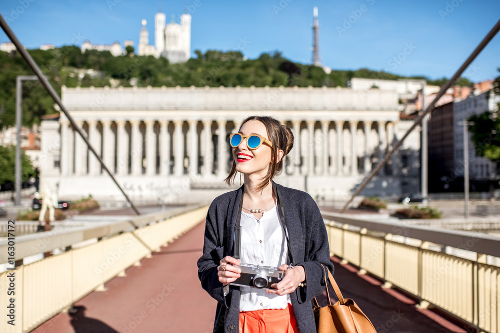 Φωτογραφία Young stylish woman standing with photo camera on the footbridge in the old town