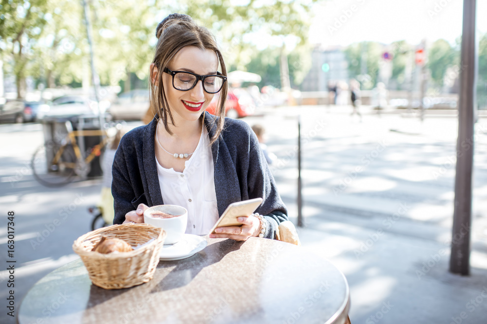 Φωτογραφία Young woman having a breakfast with coffee and croissant sitting outdoors at the