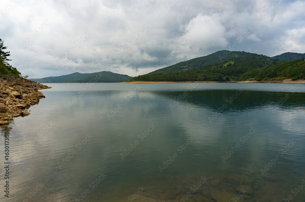 Calm lake with mountain view on overcast day