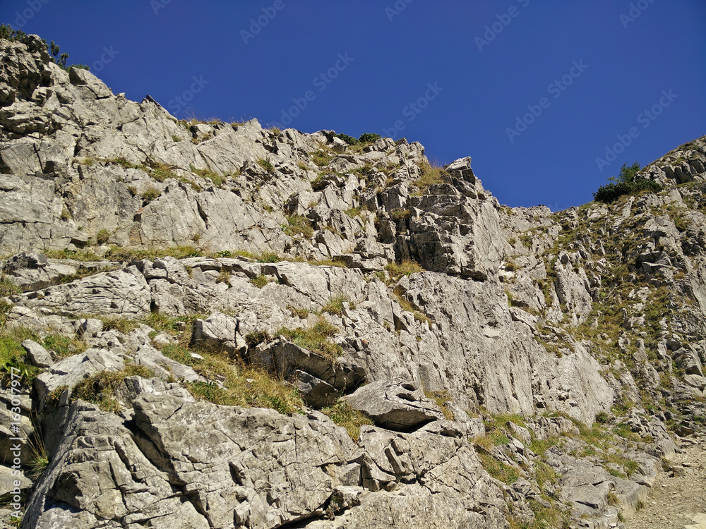 Rocky wall on the patch to the Giewont in Tatra Mountains in Poland with a blue sky Rocky wall on the patch to the Giewont in Tatra Mountains in Poland with a blue sky