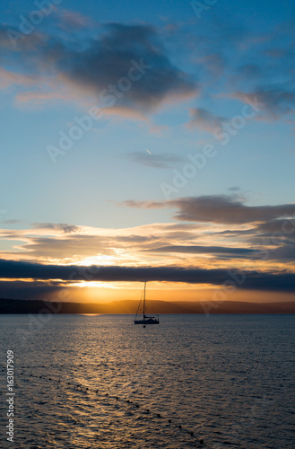 Sailboat with fallen sails in sunrise light on full sea © Tommy Lee Walker