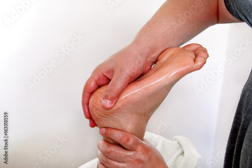 Foot massage in beauty salon, close up view. Woman having sports foot massage in spa salon. Male masseur therapist hands doing on female foot massage. Professional masseuse massaging foot of girl.