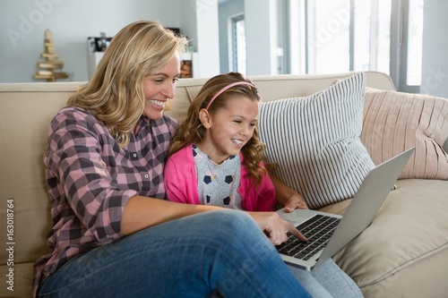 Mother and daughter using laptop in the living room