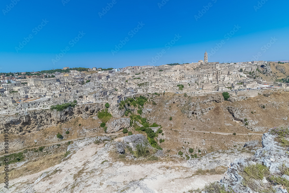 panoramic view of typical stones (Sassi di Matera) and church of Matera UNESCO European Capital of Culture 2019 under blue sky. Basilicata