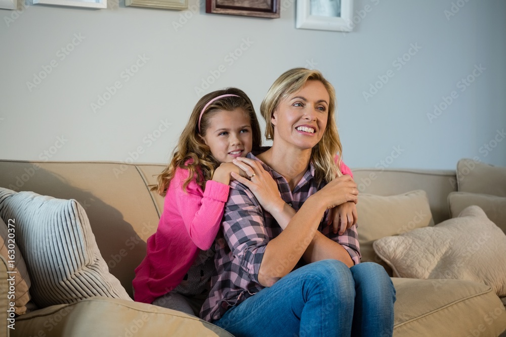 Mother and daughter embracing each other in the living room Mother and daughter embracing each other in the living room