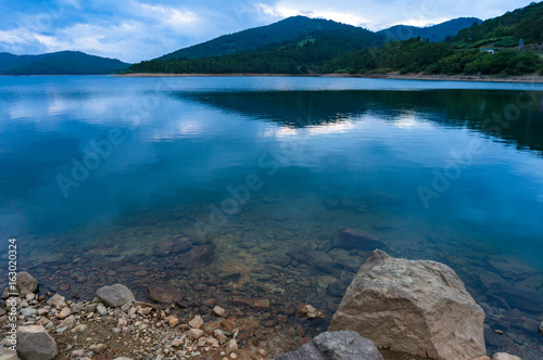 Rock shore and calm water of mountain lake