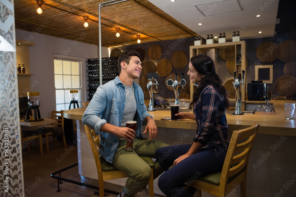 Smiling friends talking to each other at bar Smiling friends talking to each other at bar