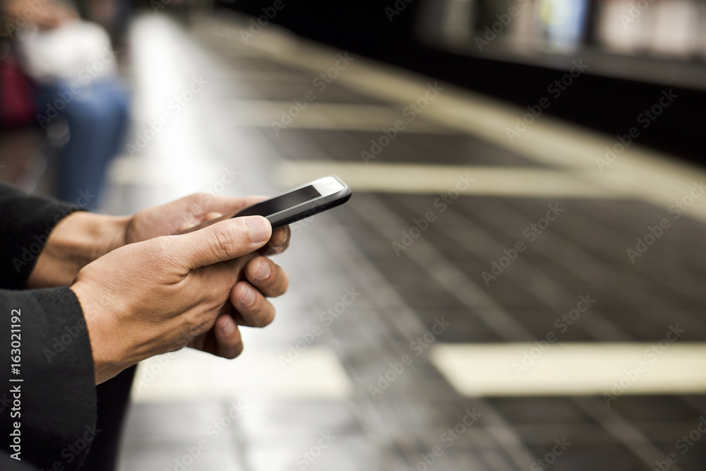 man using smartphone in underground station man using smartphone in underground station