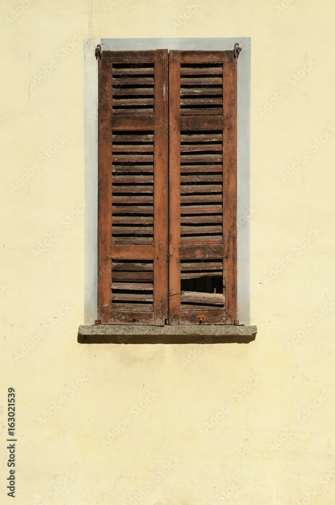 Detail of a window in a colorful wall, warm Italian sunlight and the real mediterranean atmosphere