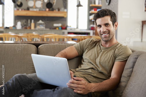 Portrait Of Man Sitting On Lounge Sofa Using Laptop © Monkey Business