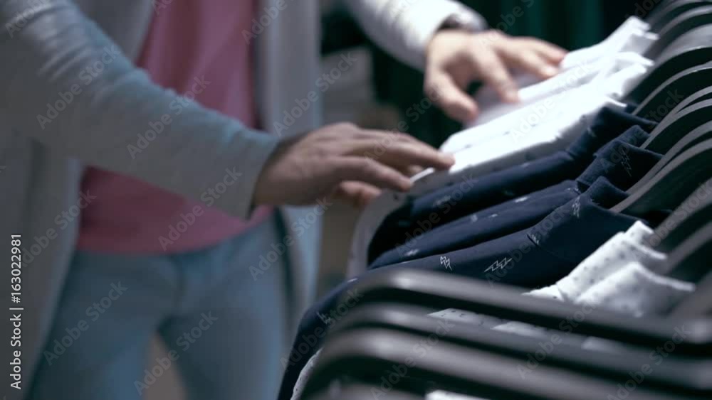 Closeup of Male Adult Choosing Shirts in Cloth Store Closeup of Male Adult Choosing Shirts in Cloth Store