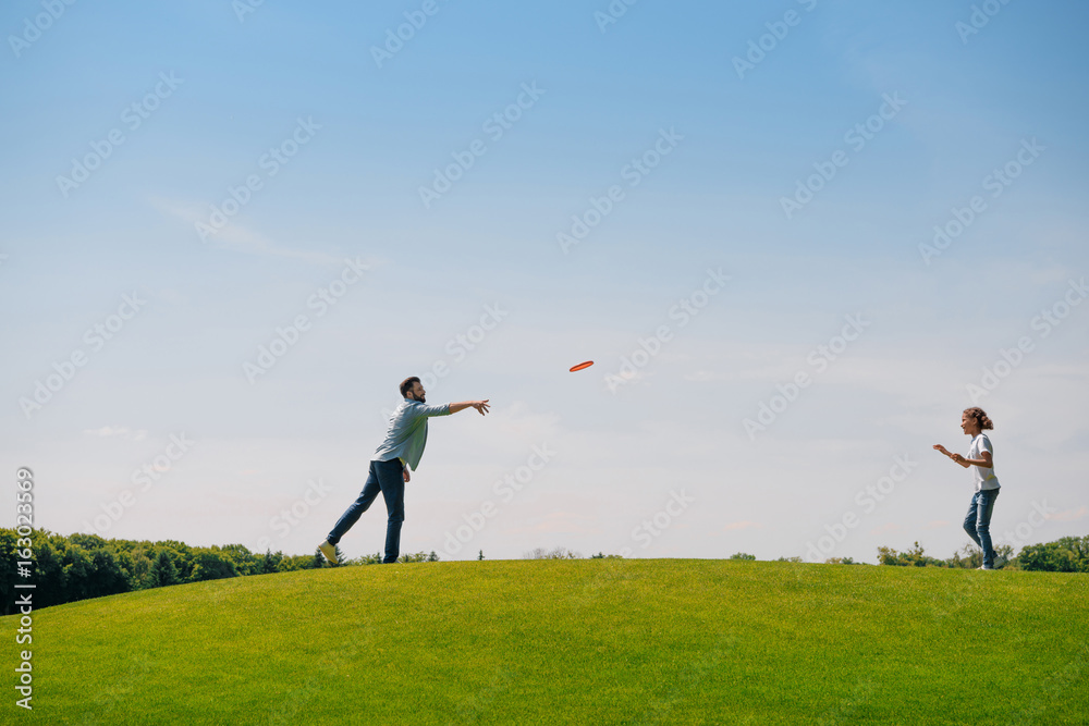 Happy father and daughter playing with flying disk on green lawn Happy father and daughter playing with flying disk on green lawn